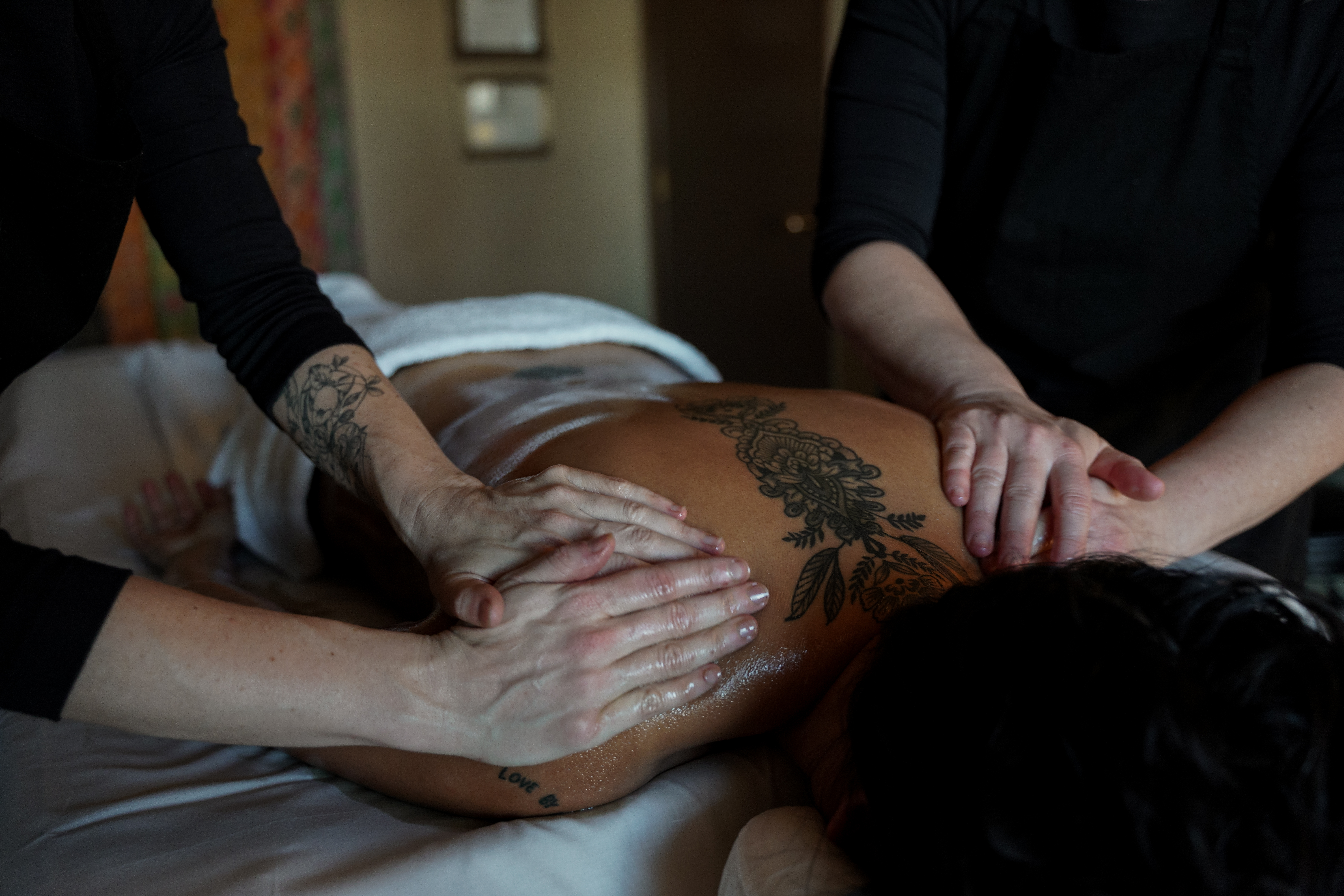 Two practitioners performing an Abhyanga oil massage treatment