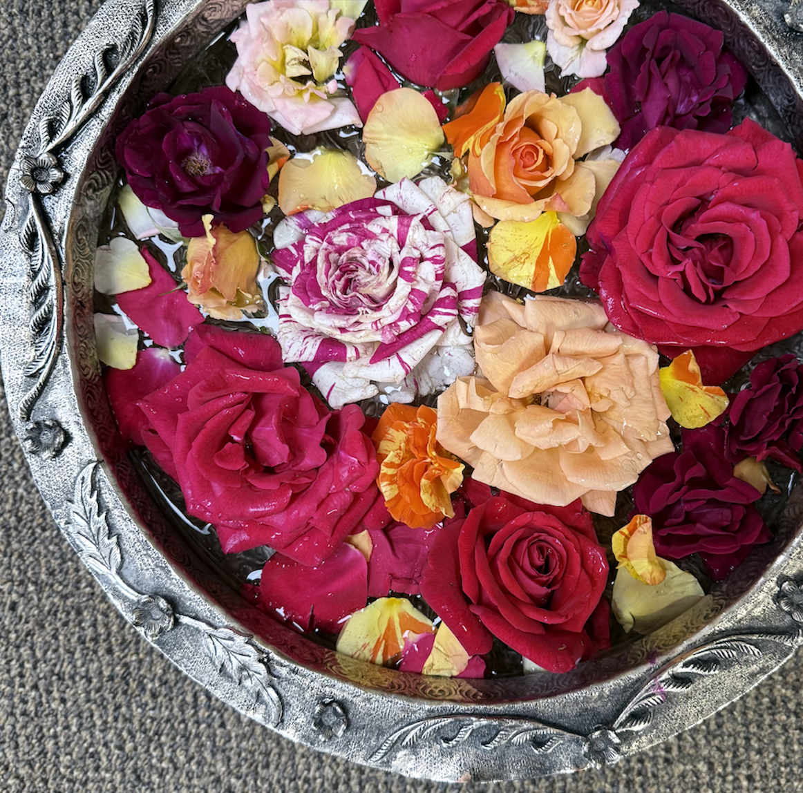 Colorful roses floating in a decorative silver bowl — used in Ayurvedic conscious conception rituals